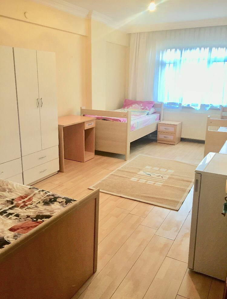 Yataklar, kişisel çalışma masaları ve dolap bulunan paylaşımlı oda